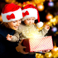 Mother with little child opens the box with gifts on christmas