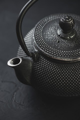 Obraz na płótnie Canvas Close-up of black cast-iron asian teapot, vertical shot