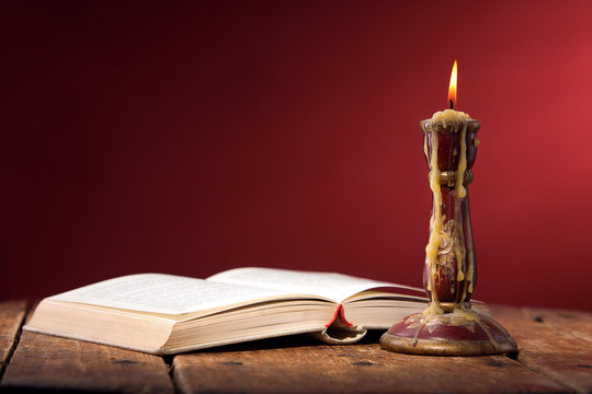 Vintage still life with open old book near candle