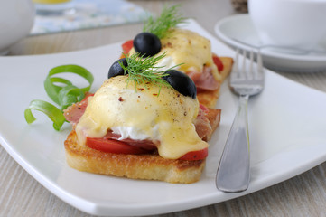 Eggs Benedict with ham and tomato on toast with cheese