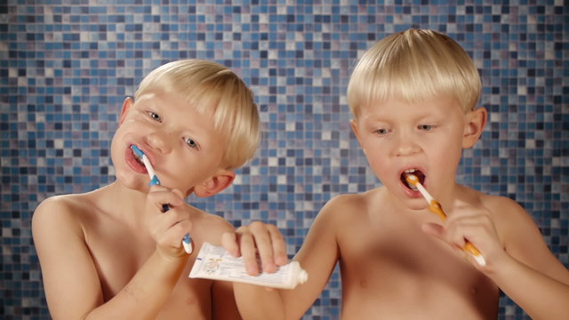 blond twin brothers brushing teeth in bathroom