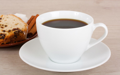 Cup of coffee and fruitcake on a saucer.
