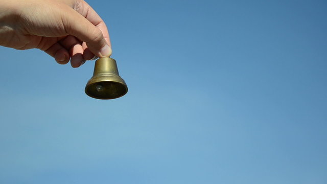 boy and girl hands jingle with silver bronze bell on blue sky