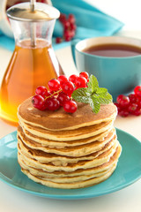 Homemade pancakes with honey and berries on a wooden table.