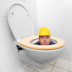 Funny repairman looking from the toilet bowl.