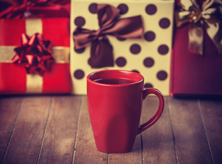 Cup of coffee and gifts at background