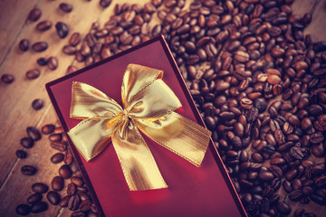 Red gift on wooden table with coffee grain