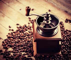 Coffee grinder with coffee grains on a wooden table