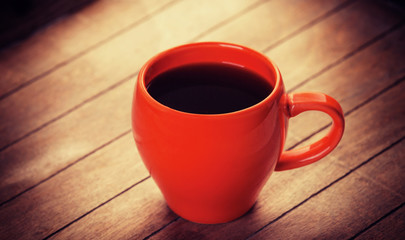 Red cup of coffee on wooden table