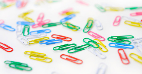 Background of multicolored paper clips on white.