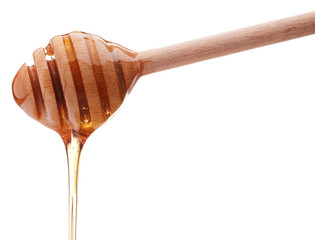 Honey dripping from a wooden honey dipper isolated on white back