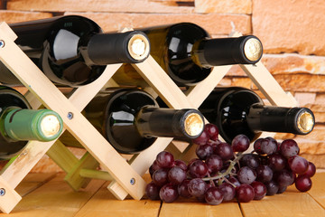 Bottles of wine placed on wooden stand on stone wall background