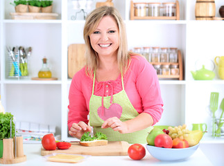 Happy smiling woman in kitchen preparing  sandwich