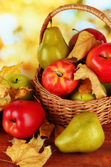 Beautiful ripe apples and pears with yellow leaves in basket