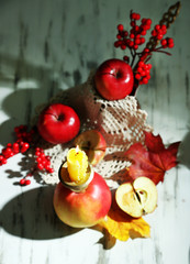 Composition with apples and candle on wooden background