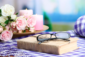 Composition with old book, eye glasses, candles, flowers and