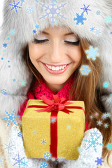 Beautiful smiling girl in hat with Christmas gift close up