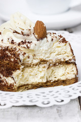 Tiramisu cake on white plate. Wooden background, selective focus
