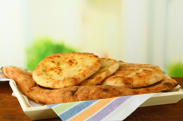 Pita breads on tray on table on bright background