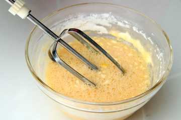 Cooking, whipping eggs with electric whisk in bowl, close up