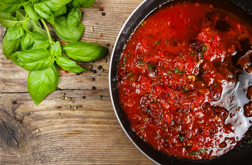 Red sauce made of dried tomatoes on frying pan. Wooden back