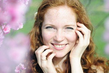 beautiful red-haired girl among the flowering trees