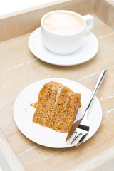 piece of honey cake and cup of cappuccino on a tray