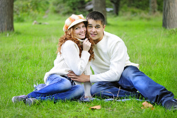 Young beautiful couple on green grass in autumn