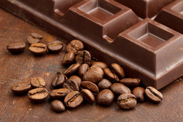 dark chocolate bar and coffee beans on wooden table