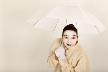 Der Clown hält einen weißen Schirm in der Hand