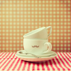 Coffee cups with hipster  mustache on checked tablecloth