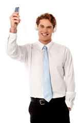 Cool young businessman enjoying music