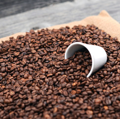 Cup of coffee filled with coffee beans against wooden background