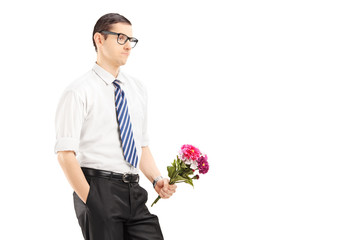 Worried young man with tie holding a bouquet of flowers