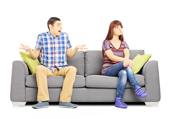 Young couple sitting on a couch during an argument