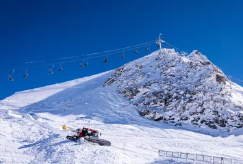 Fotobehang Chair lift and snow groomer in Alps © kilhan