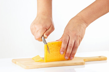 Female hand with a knife sliced cheese on a white background