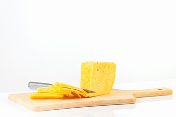 Sliced cheese with a knife on a cutting board closeup