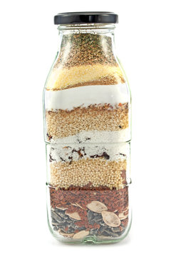 Decorative glass bottle with seeds isolated on white