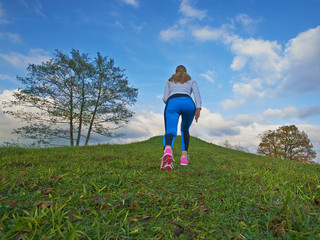 Pretty female going up the hill to clouds