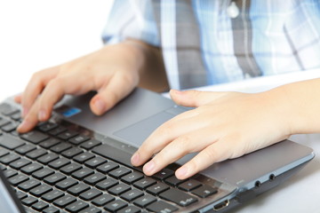 boy's hand typing on laptop keyboard
