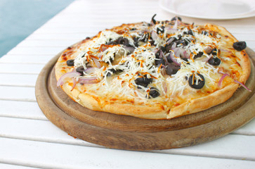 mediterranean pizza on wooden round plate