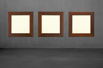 Three blank wooden frames on concrete wall
