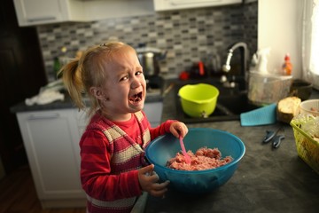 Little girl cooking and crying