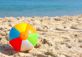 Obraz premium Day at the beach with a beach ball in the foreground.