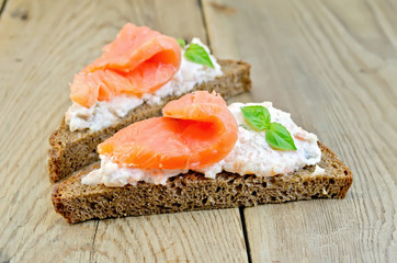 Sandwiches on bread with salmon and basil on board