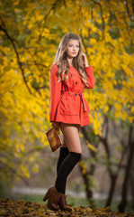 Beautiful elegant woman with orange coat posing in park