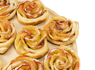 Obraz na płótnie Canvas Sweet rolls with apples in the form of roses on wooden board on