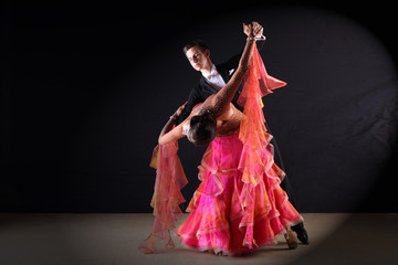 Latino dancers in ballroom against black background