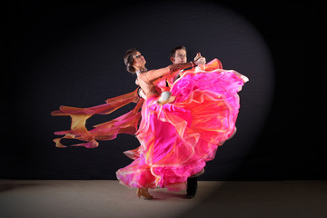 Latino dancers in ballroom against black background